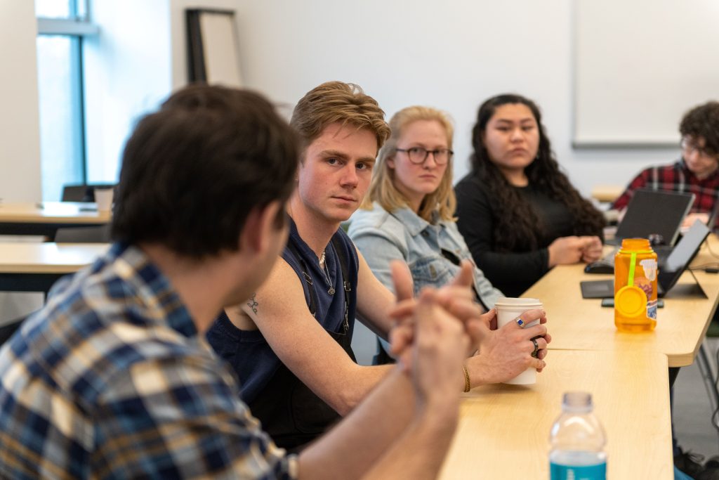 a group of students sits around a table, discussing a topic. 