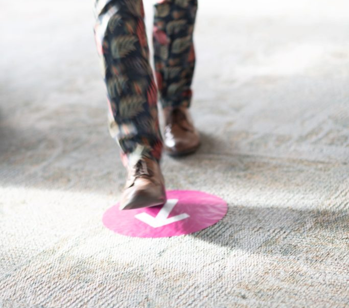 a close look at a person's legs walking on a carpet that has an arrow pointing forward. 